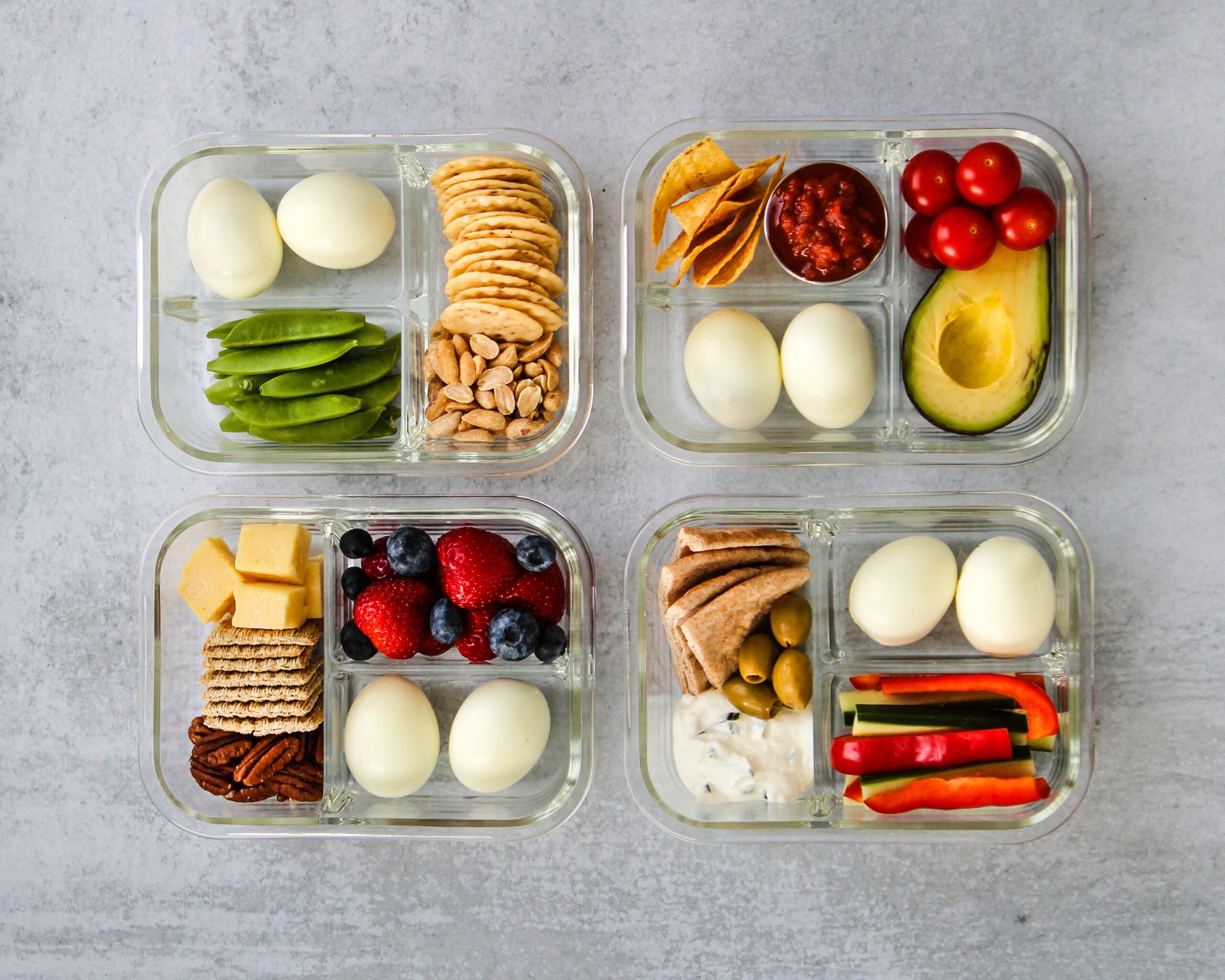 meal prep protein snack boxes with hard boiled eggs, cheese, nuts and vegetables