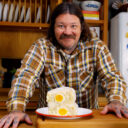 Matty Matheson holding a chopped BLT egg salad sandwich packed with bacon and cheddar.